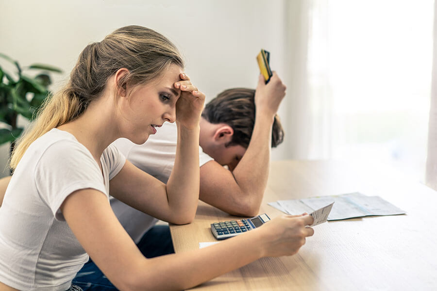 A stressed young couple wondering how to consolidate debt to juggle their growing bills.
