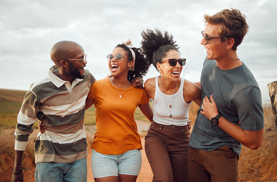 A group of four friends smile and take a walk outside.
