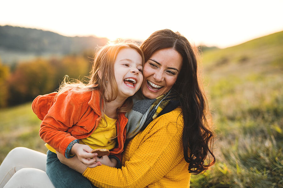Mom holding her daughter outdoors, both smiling, representing the possibilities a personal line of credit can bring to family moments.