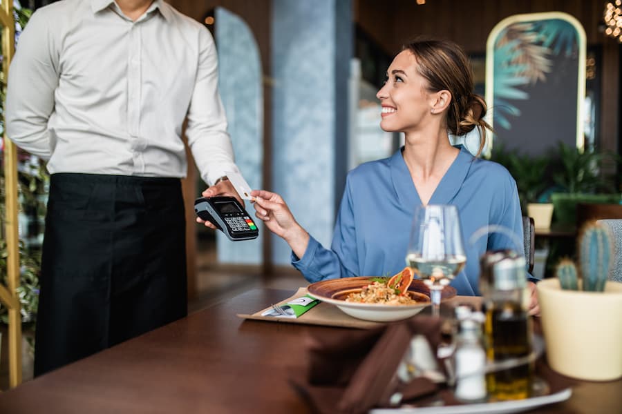  A woman pays for her meal at a restaurant with her Visa Cash Back Card.